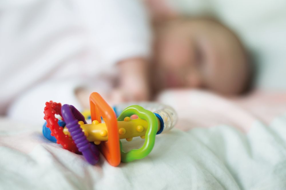 baby sleeps near rattles toy